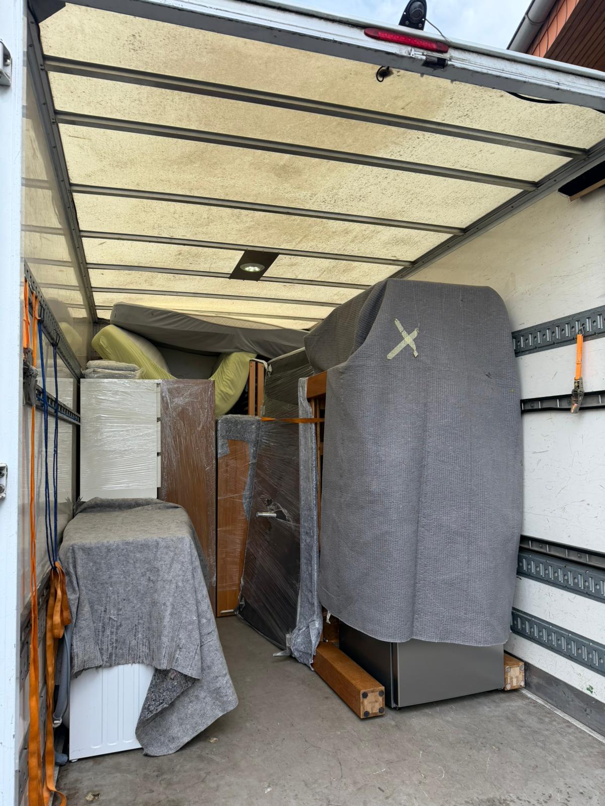 Umzugswagen von Blitz mit verpackten Möbeln und Möbeldecken sicher verladen
