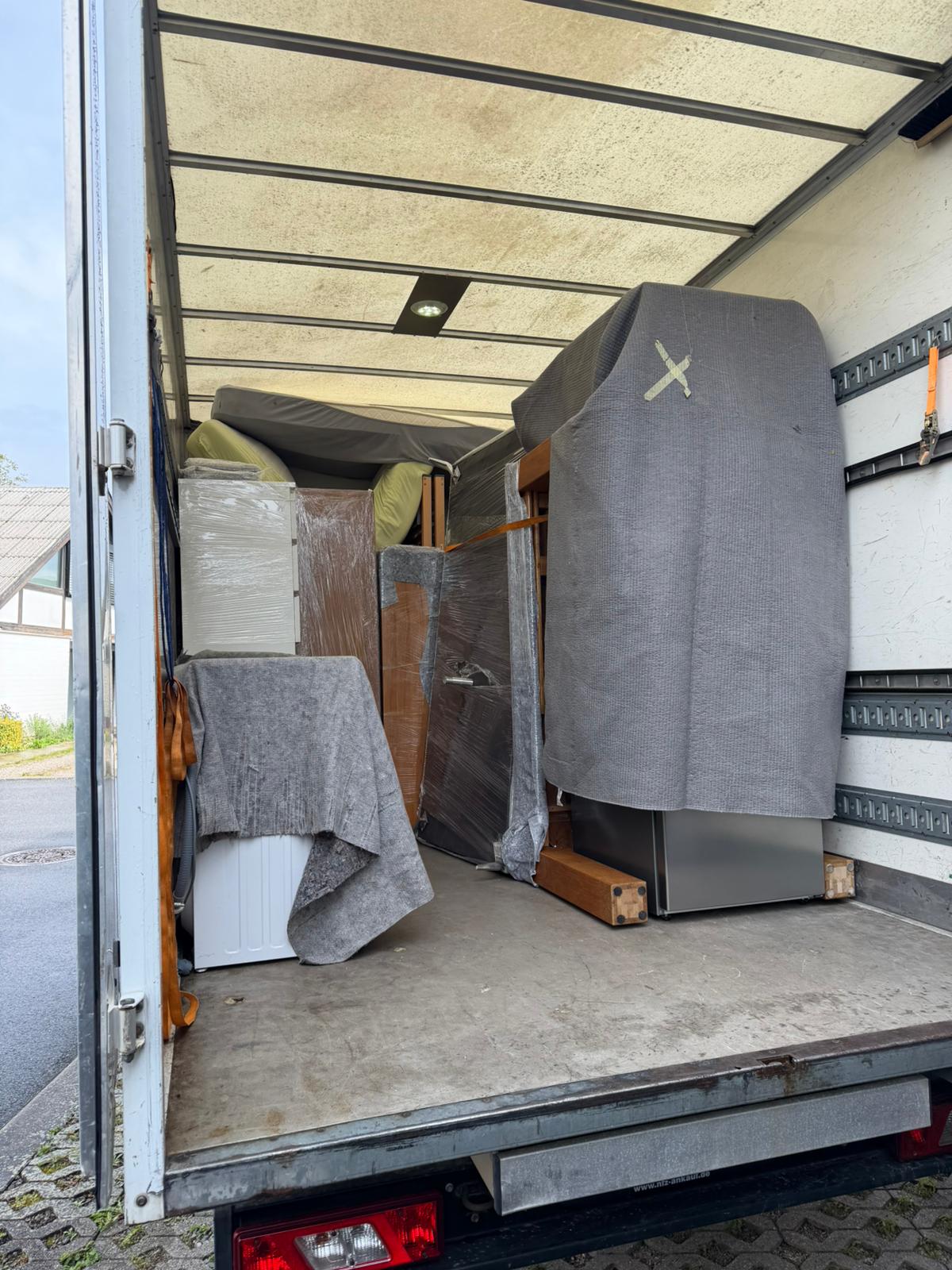 Innenraum des Umzugswagens mit verladenen Möbeln und Haushaltsgeräten